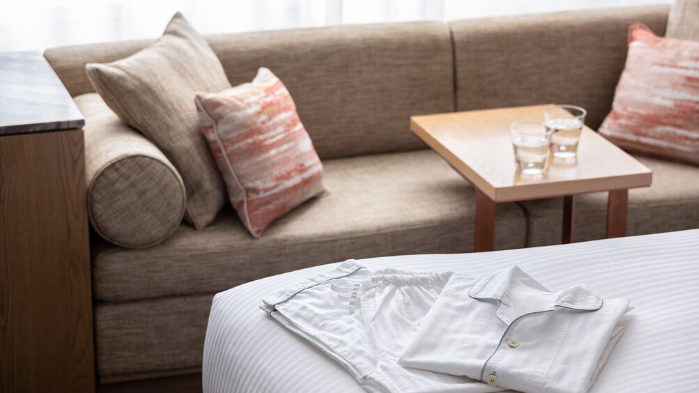 Ein Hotelzimmer mit Bett, Sofa, einem kleinen Tisch mit Gläsern und einem Nachttisch.