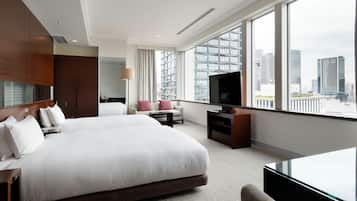 Une chambre d’hôtel moderne avec un grand lit, une télévision, un canapé et une vue sur la ville.