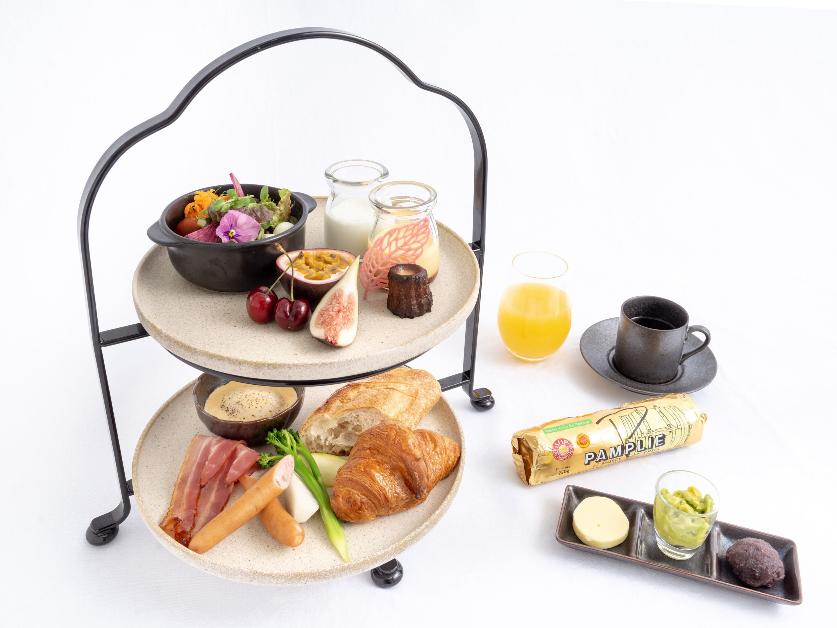 A breakfast setup with a fruit bowl, pastries, and a croissant on a tiered stand.