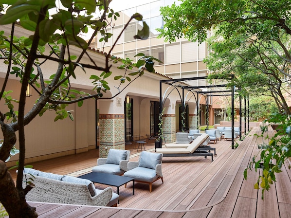 Un patio al aire libre con mobiliario de mimbre, una terraza de madera y una estructura de pérgola.