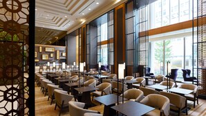 Een ruime hotel lobby met meerdere zithoeken, grote ramen met uitzicht op de stad, en een modern plafondontwerp.
