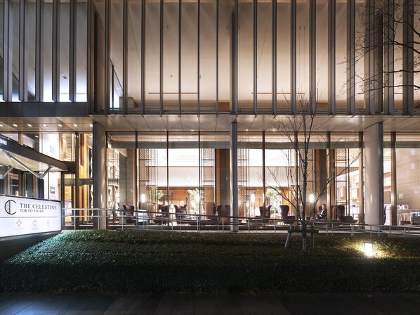 Un edificio moderno con ventanas amplias y un espacio exterior con asientos.