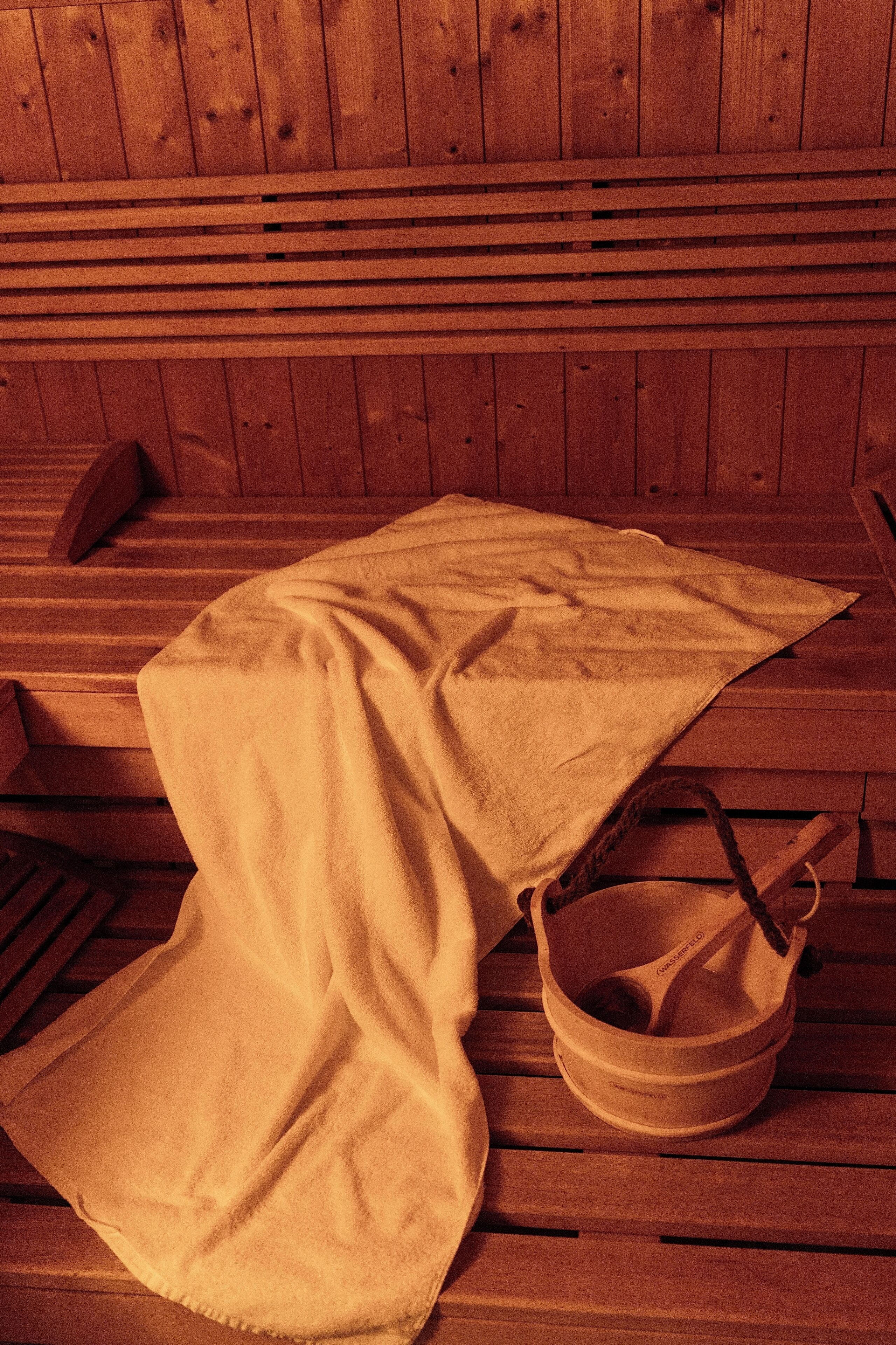 A wooden bench with a towel and a wooden bucket.