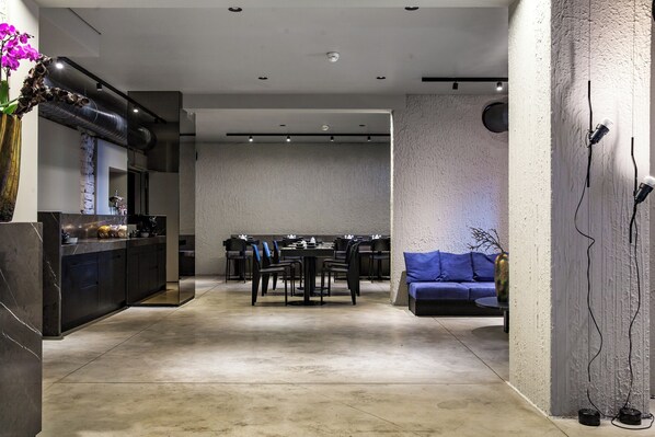 A modern interior with a dining area, a sofa, and a kitchen counter. - The Suite Garden Hotel (Frankfurt)