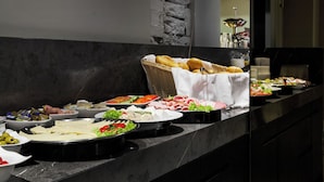 Een buffet met diverse gerechten, waaronder vleeswaren, kazen en groenten.