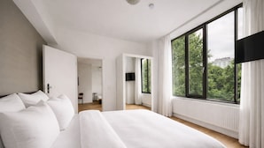 Een moderne hotelkamer met een groot bed, uitzicht op groen en een aparte badkamer.
