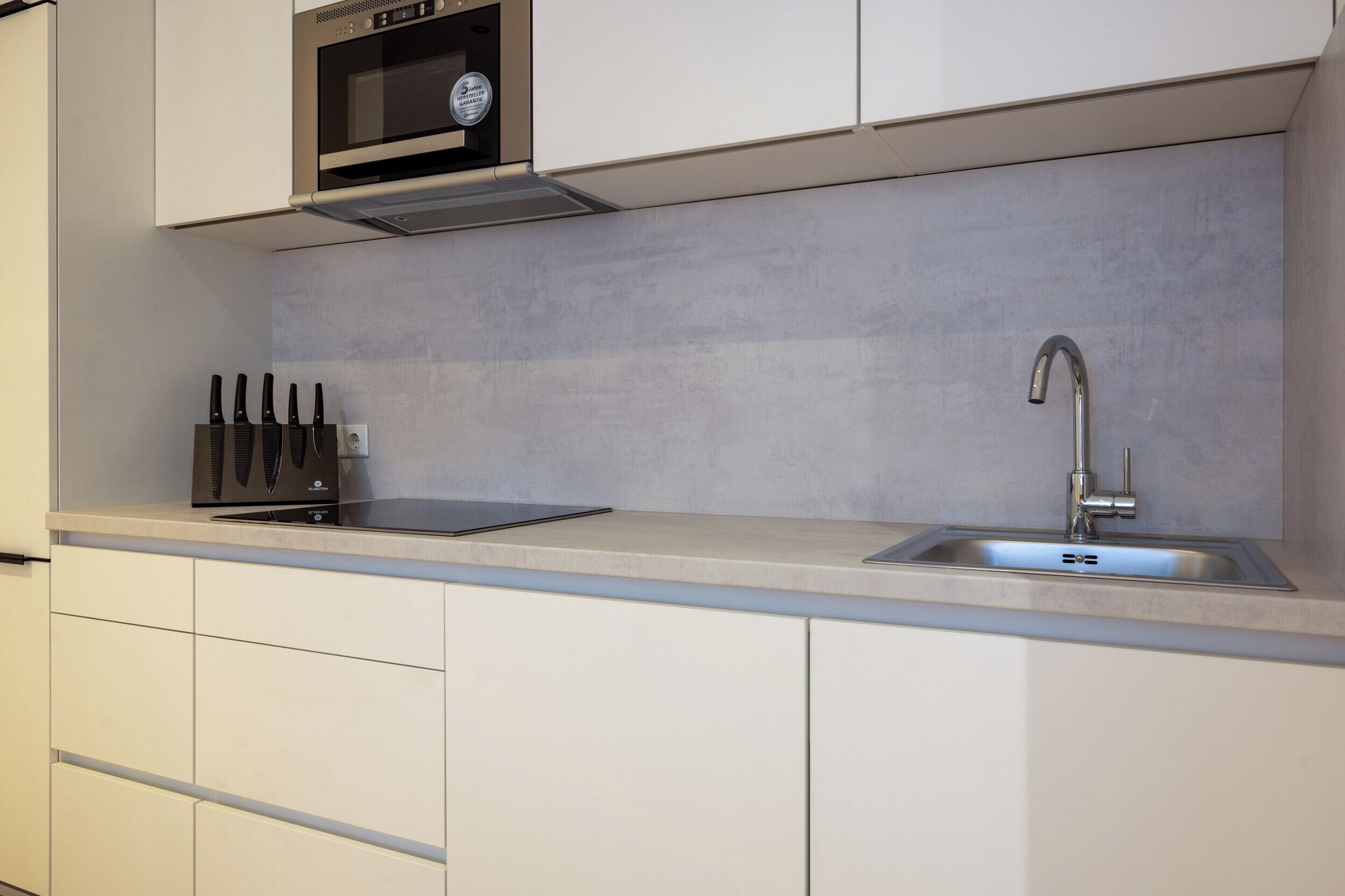 A kitchen with a microwave, sink, and knife block.