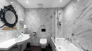 A modern bathroom with a marble sink, toilet, and bathtub, equipped with a handheld showerhead and grab bars.