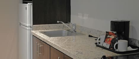 Una cocina moderna con refrigerador empotrado, pileta doble y cafetera sobre la encimera.