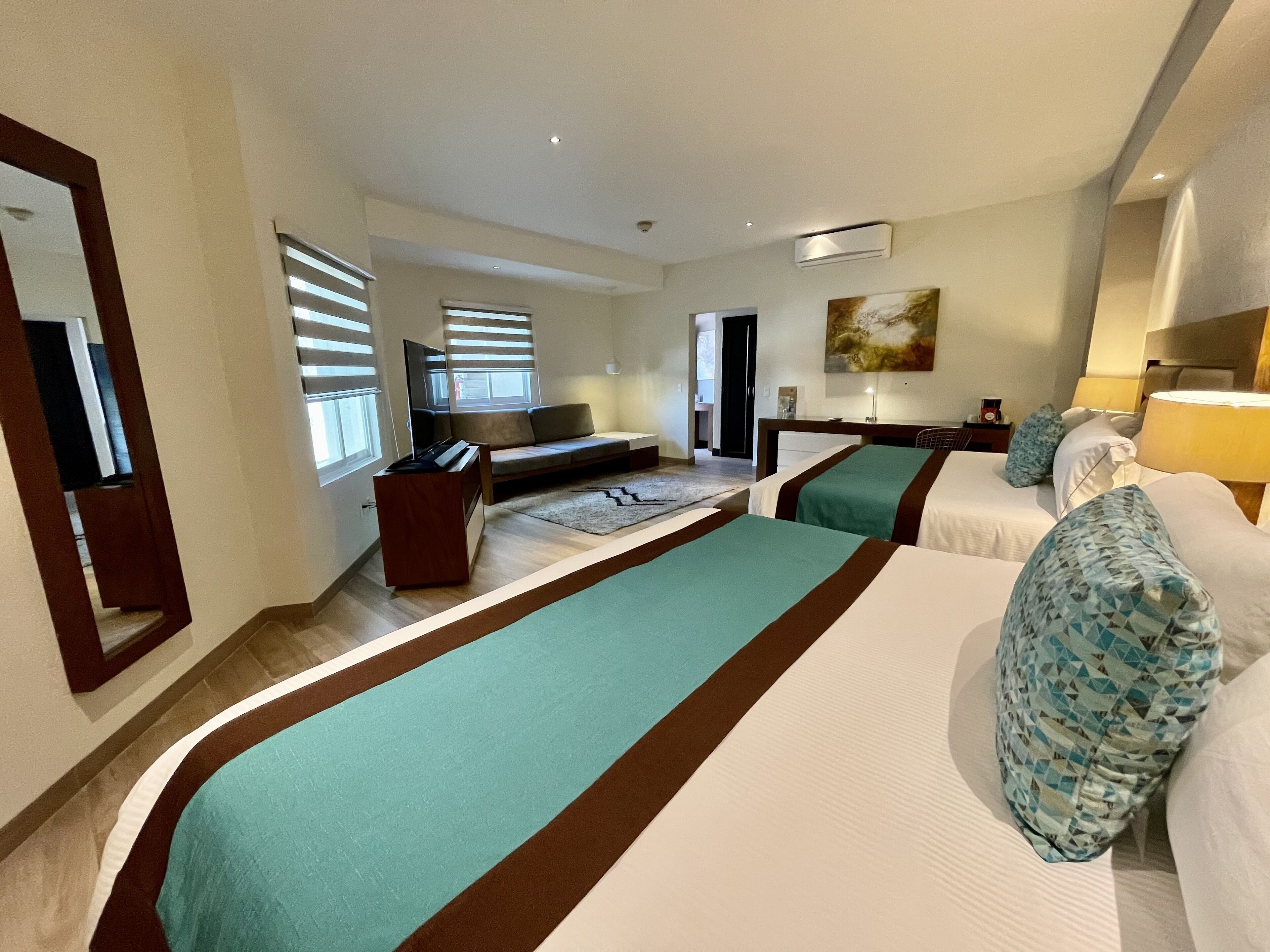 Una habitación de hotel con una cama grande, un sofá, un escritorio y una televisión.