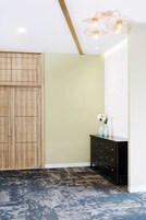 A room with a wooden wardrobe, a black dresser, and a patterned carpet.