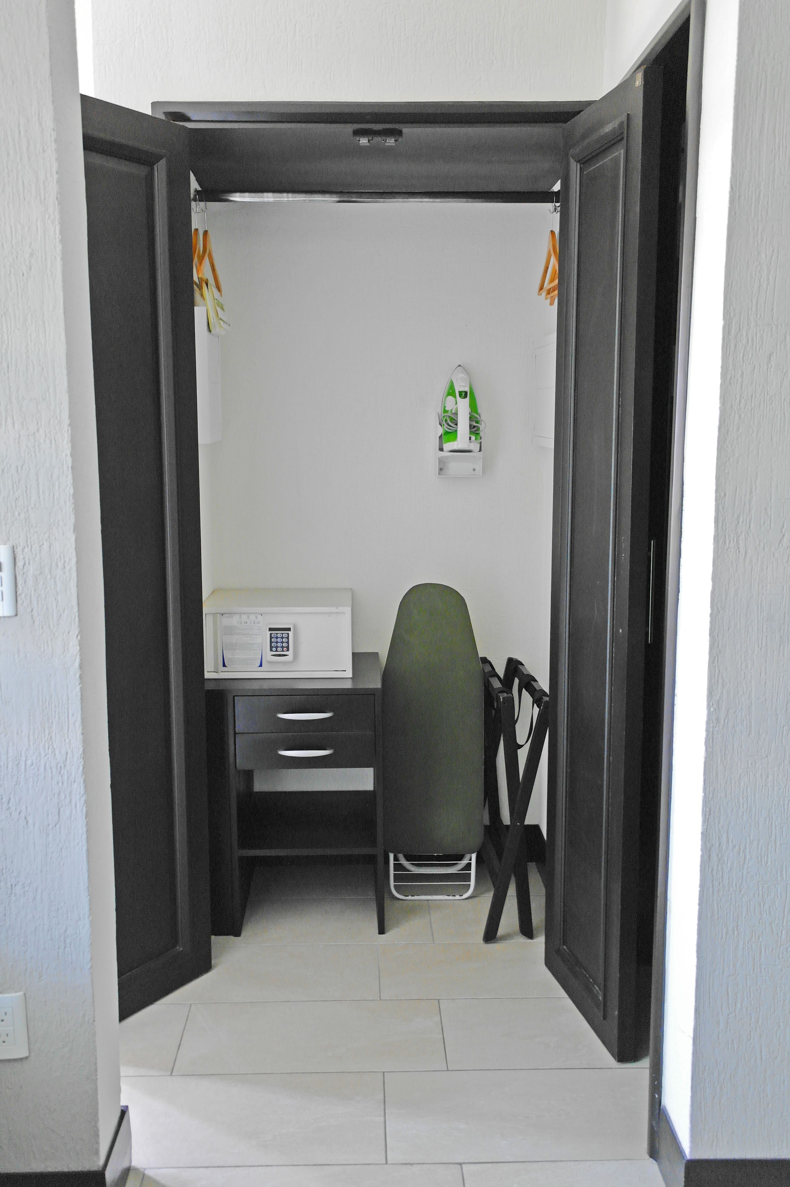 Una habitación pequeña con escritorio, silla y un estante.