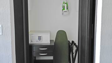 Una habitación pequeña con escritorio, silla y un estante.