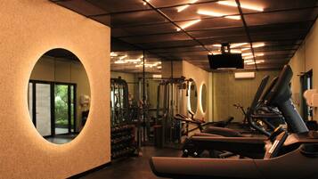 A gym with exercise equipment, a large mirror, and a television on the wall.