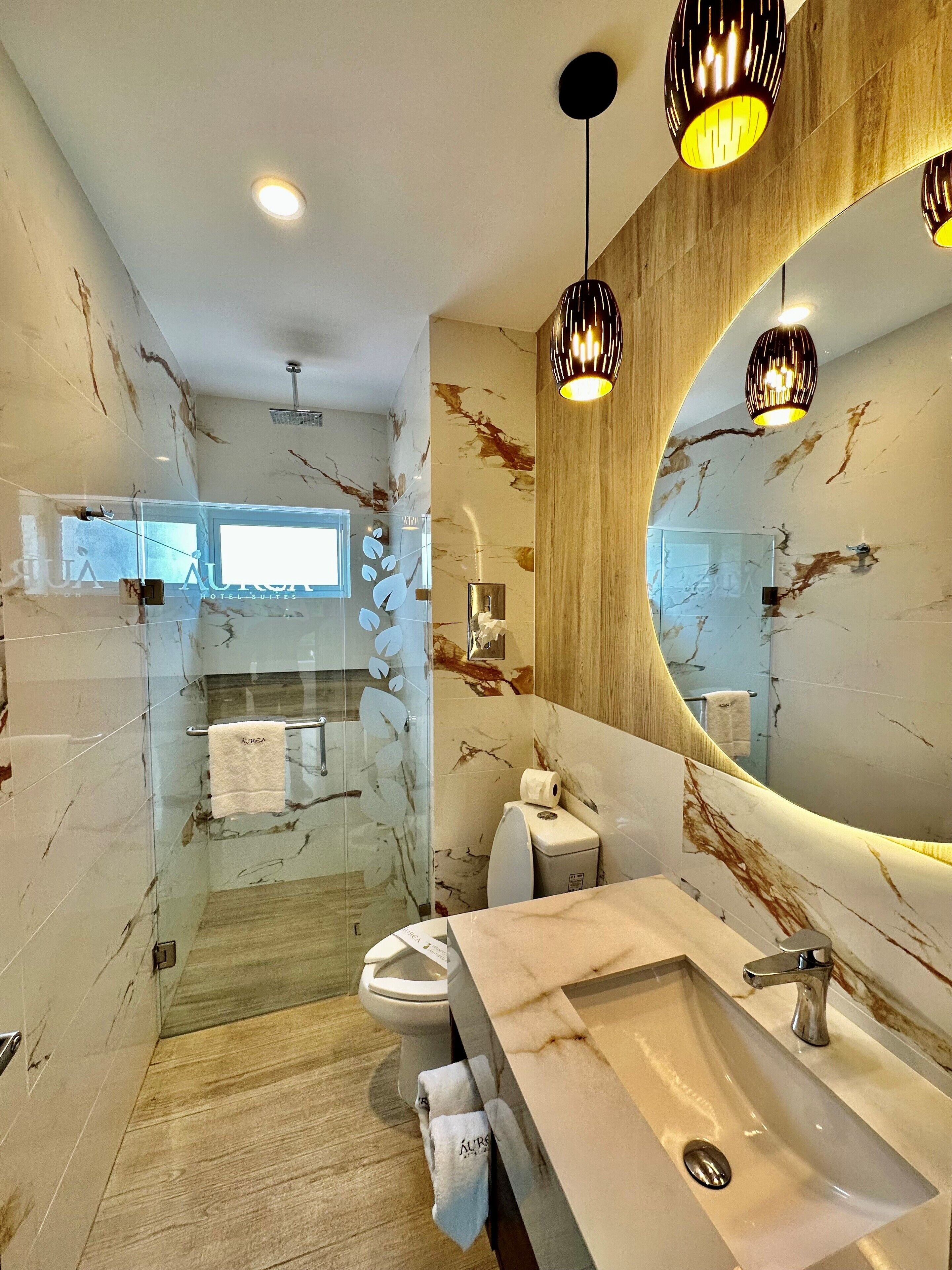 A modern bathroom with a marble backsplash, a large mirror, and a wooden vanity.