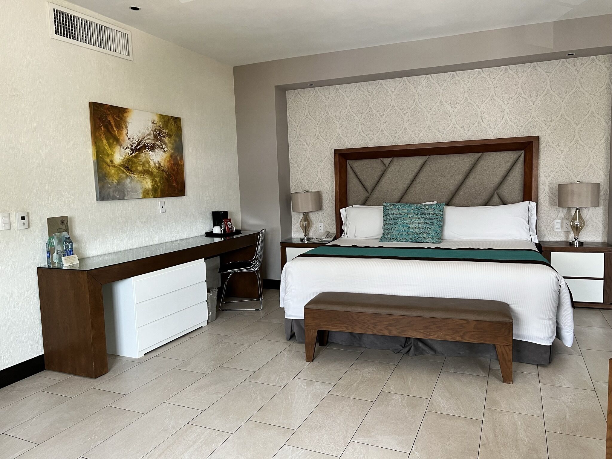 Una habitación de hotel con una cama, mesitas de noche, un escritorio y una silla.