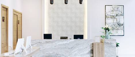 A modern reception area with a marble counter, wooden accents, and pendant lighting.