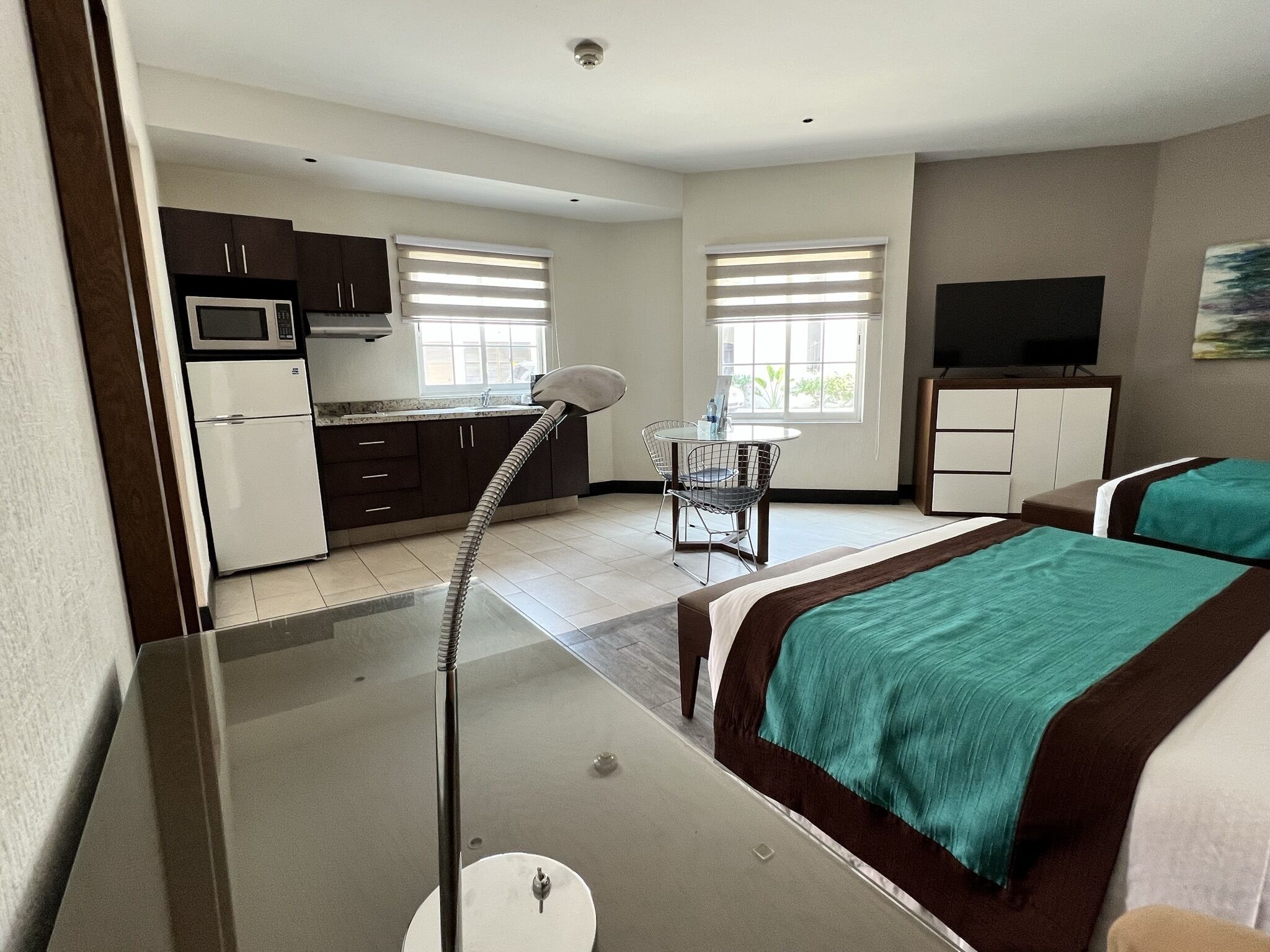 Een hotelkamer met een bed, een bureau, een stoel, een televisie en een kitchenette.