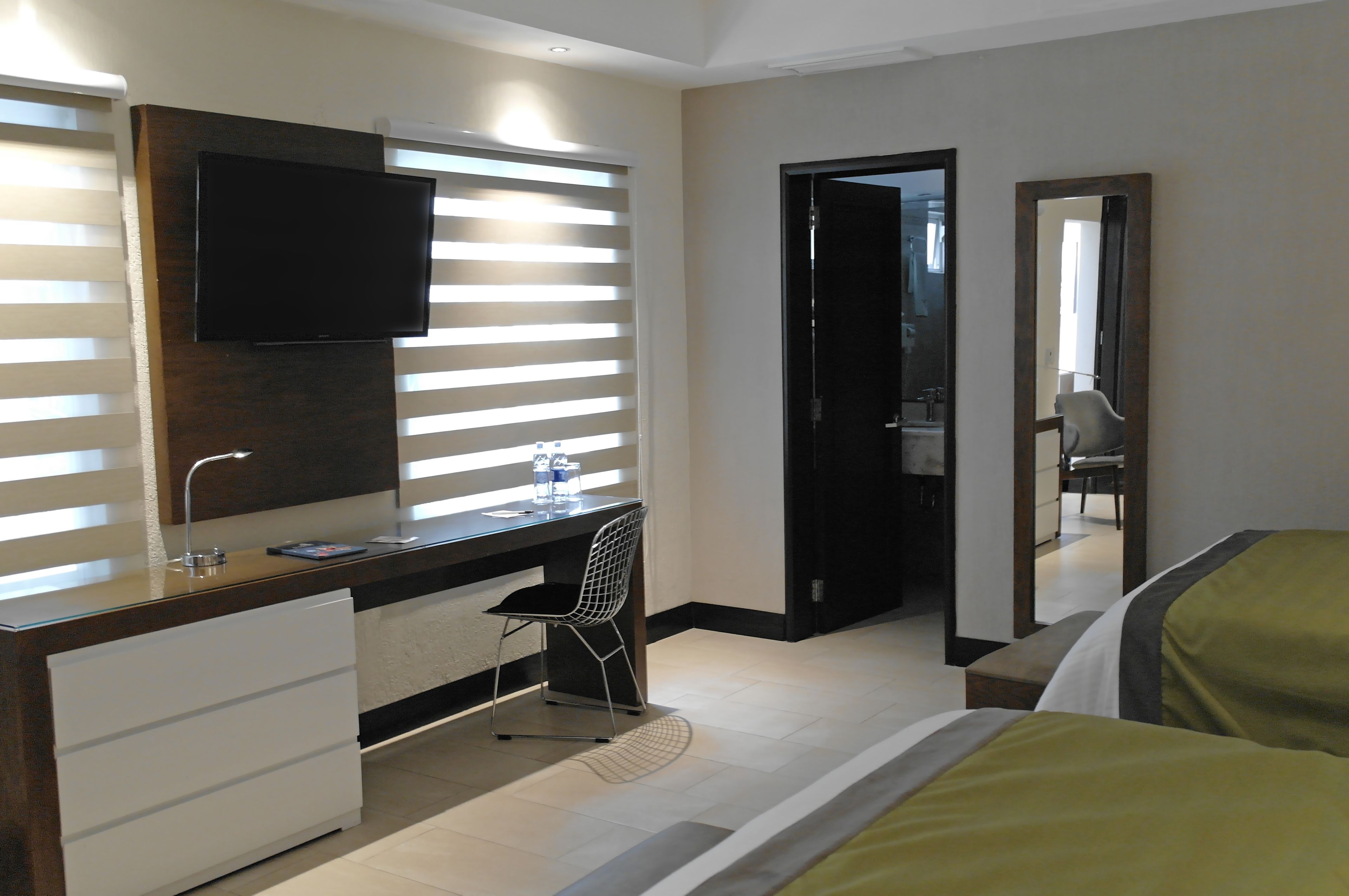 Una habitación de hotel con escritorio, silla, cama y televisión instalada en la pared.