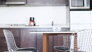 A modern kitchen with dark wood cabinets, a stainless steel microwave, and a white pendant light.