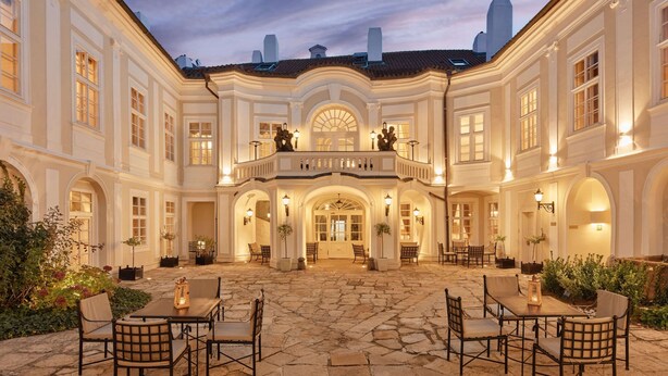 A spacious courtyard with stone flooring, multiple seating areas, and a central entrance with a balcony. - The Mozart Prague by Accor (Prague)