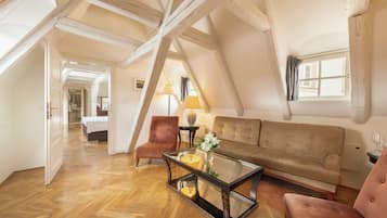 Um quarto estilo loft com vigas de madeira aparentes, uma mesa de centro de vidro, um sofá e uma poltrona.