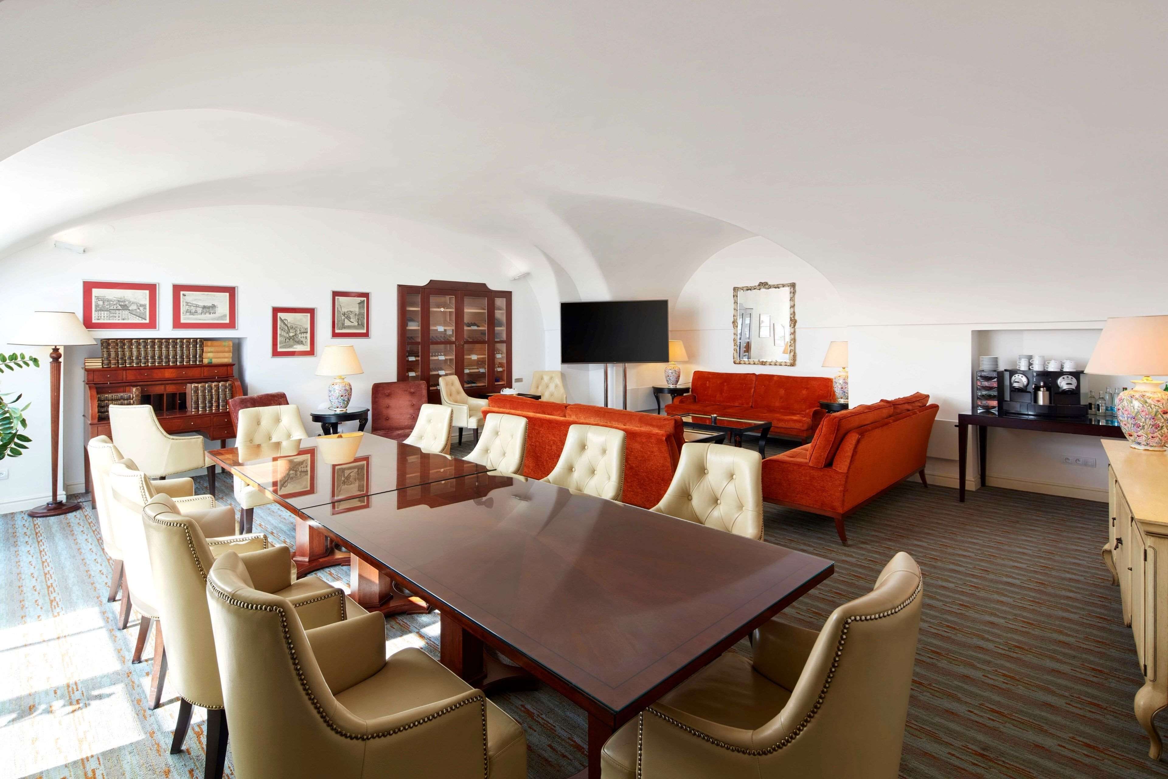 Una habitación amplia con una gran mesa de madera rodeada de sillas, un sofá rojo y una televisión.