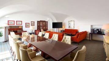 Una habitación amplia con una gran mesa de madera rodeada de sillas, un sofá rojo y una televisión.