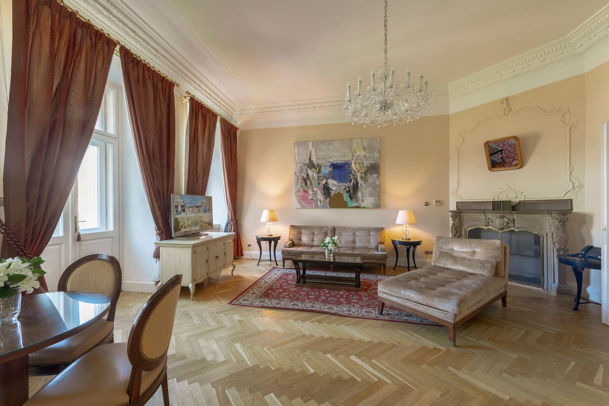 A spacious living room with a fireplace, a chandelier, and a large abstract painting on the wall.