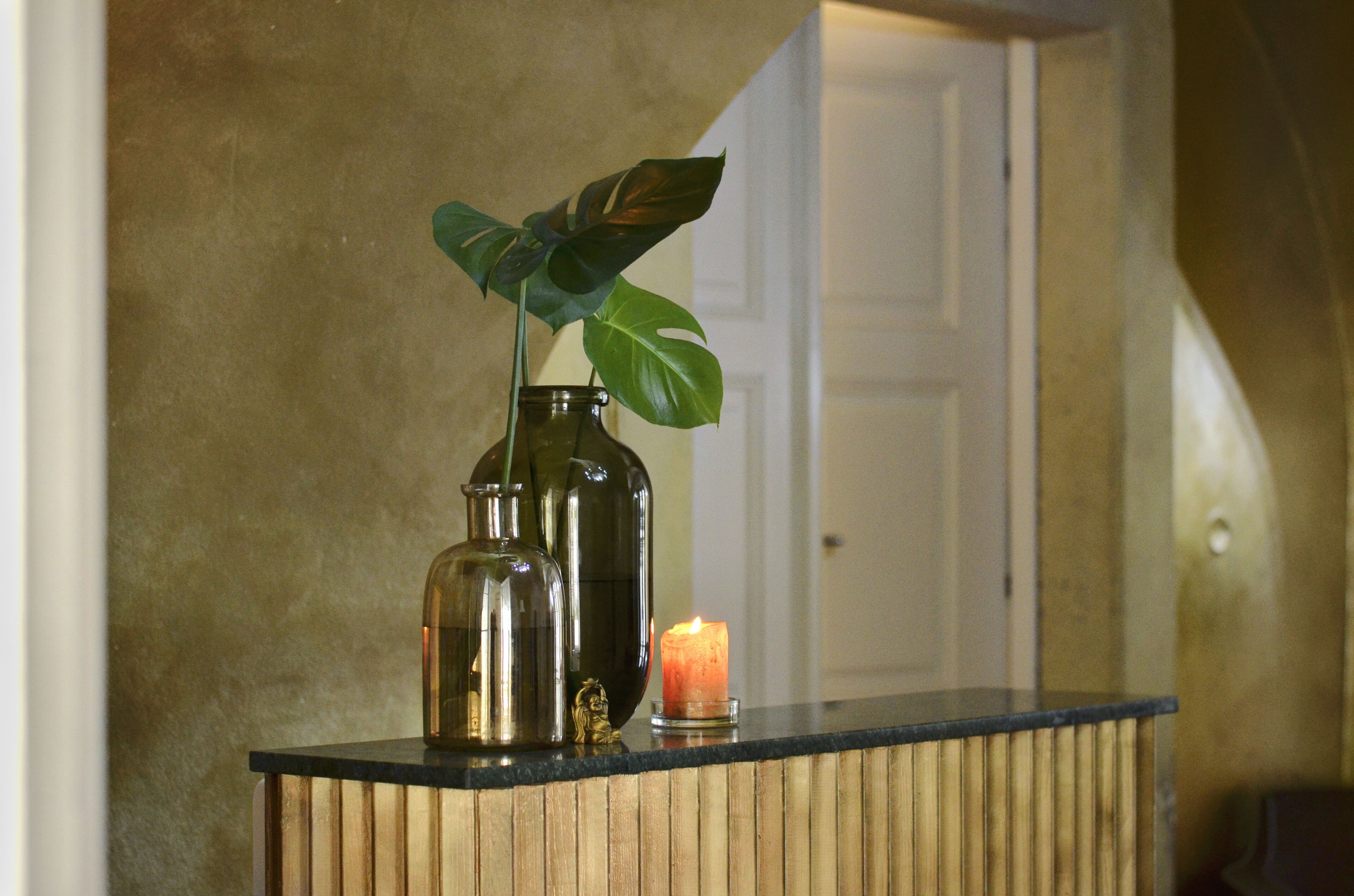 A wooden counter with two glass bottles and a candle.