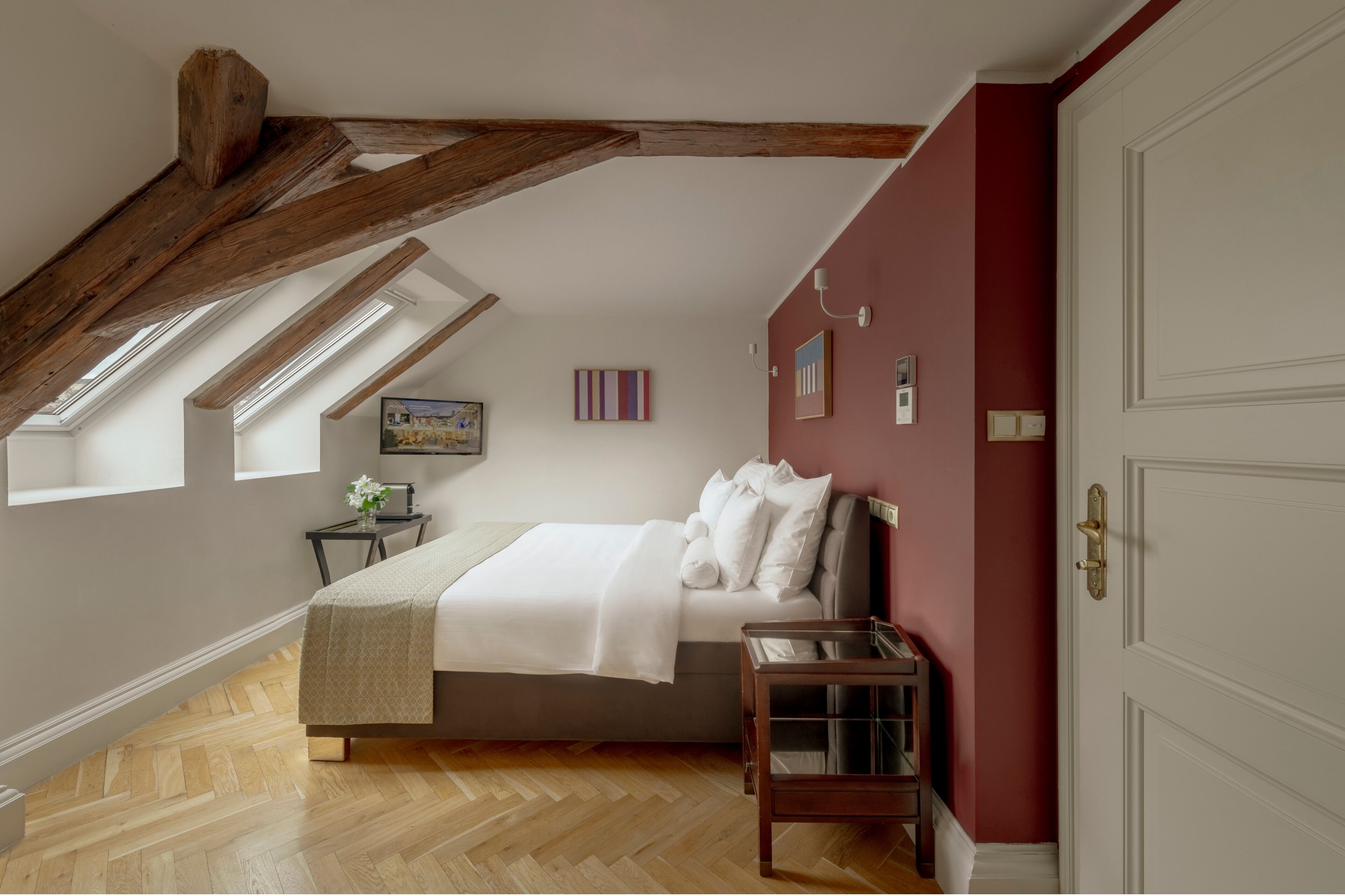 A bedroom with a bed, a bedside table, a window, and a door.