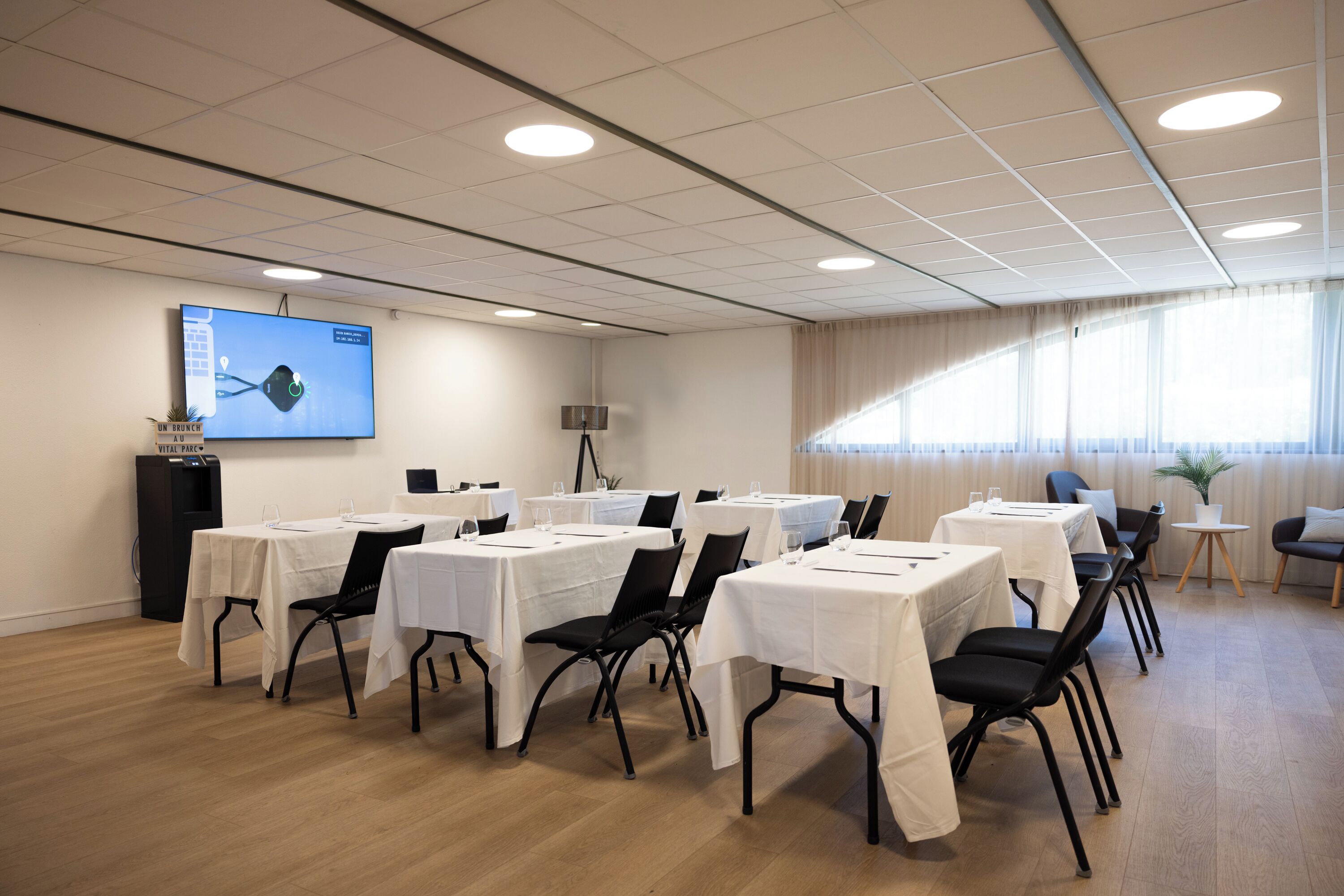 A conference room with multiple tables and chairs, a projector screen, and a podium.