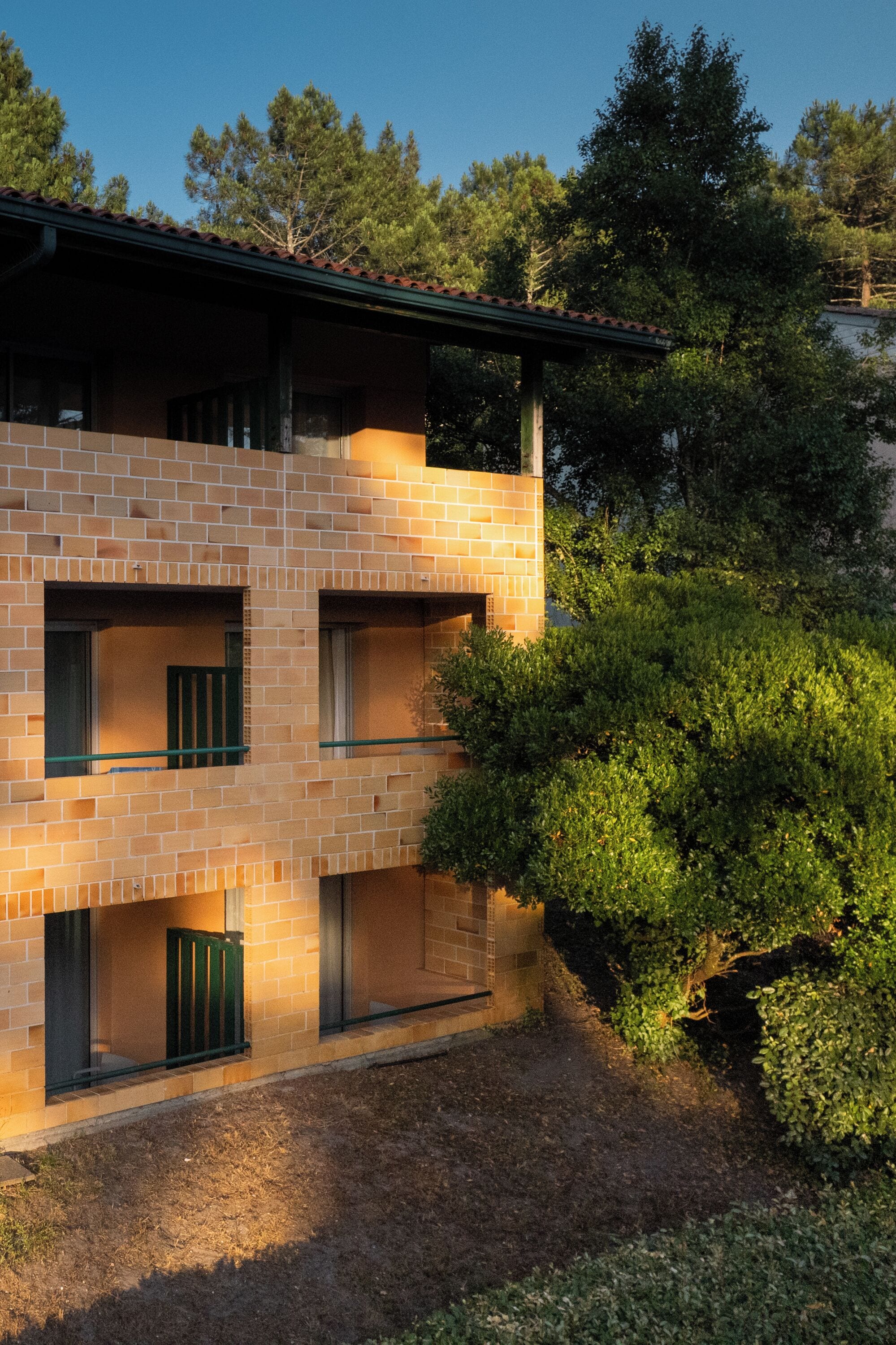 A multi-story building with a brick facade, balconies, and a garden area.