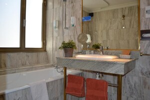 Un baño con lavamanos de mármol, una bañera y un espejo grande.