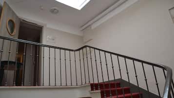 A staircase with red carpeted steps and a black railing, leading to an upper floor.