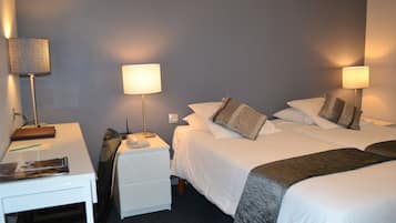 A hotel room with two beds, a desk, and two bedside lamps.