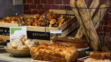 Une vitrine de boulangerie présentant divers produits de boulangerie, notamment du pain et des pâtisseries, avec des étiquettes indiquant les options sans gluten.
