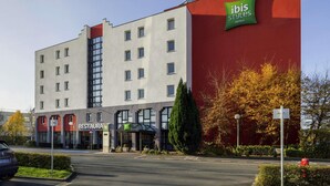 A hotel with a modern design, featuring a restaurant, a green 'ibis Styles' sign, and a parking lot. - ibis Styles Lille Marcq en Baroeul (Marcq-en-Baroeul)