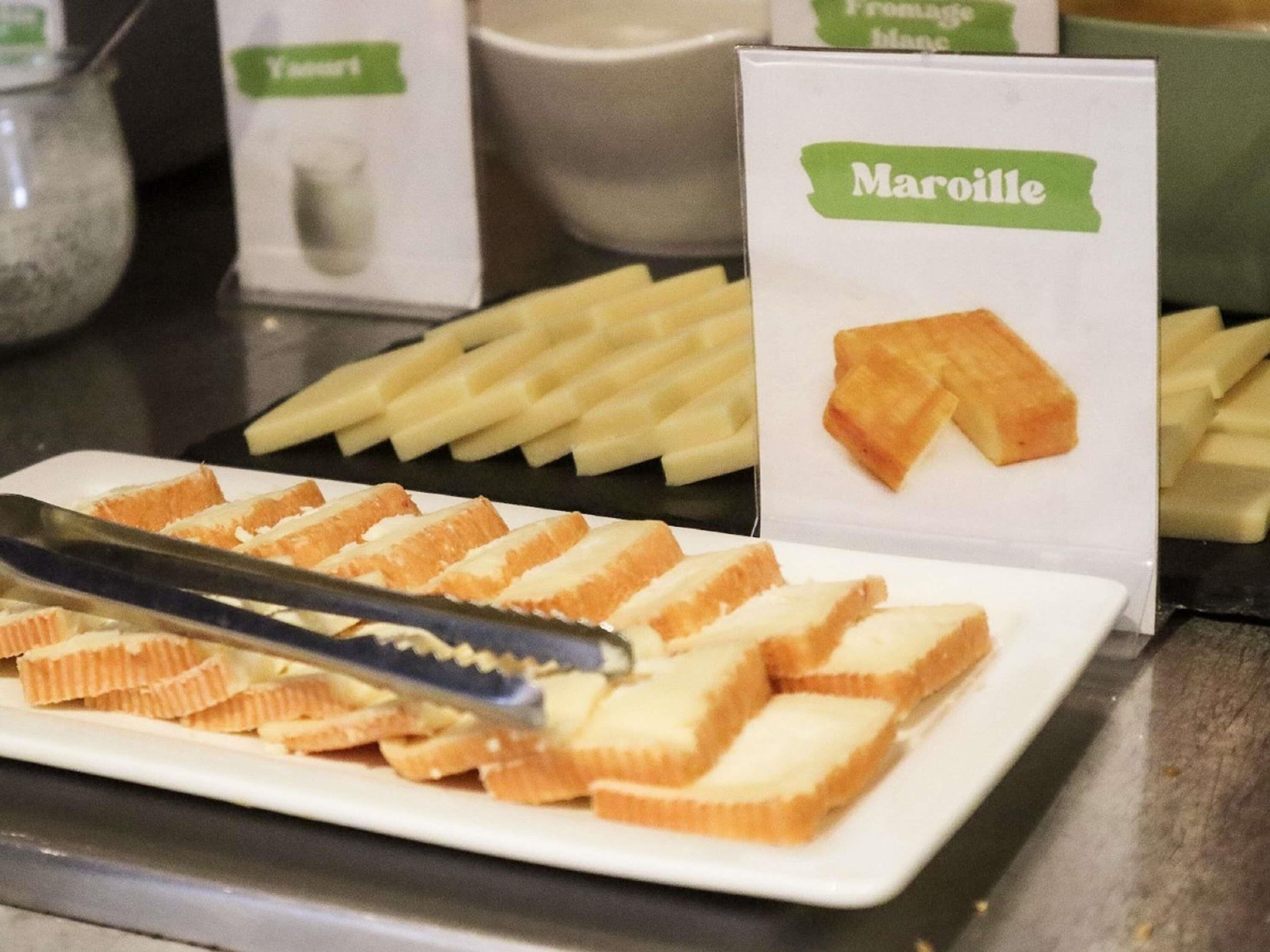 En tallerken med macarons på en hvid bakke, med et skilt med teksten 'Maroille' i baggrunden.