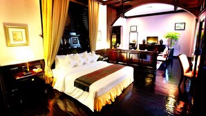 A hotel room with a large bed, a desk, and a chair. There is a plant on the desk and a lamp on the nightstand. - Ree Mohasambath Hotel & Resort  I (Siem Reap)