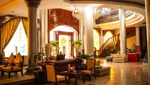 A spacious lobby with a grand staircase, multiple seating areas, and large columns. - Ree Mohasambath Hotel & Resort  I (Siem Reap)