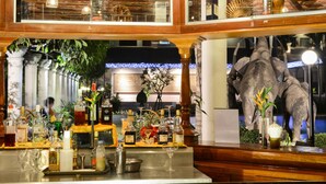 A bar area with a variety of bottles and glasses, wooden decor, and a large aquarium with fish. - Ree Mohasambath Hotel & Resort  I (Siem Reap)