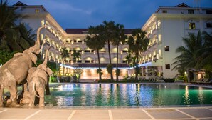 A hotel with a swimming pool, palm trees, and a large elephant statue. - Ree Mohasambath Hotel & Resort  I (Siem Reap)