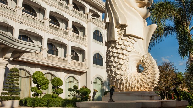 A large white building with multiple balconies and a prominent lion statue in front. - Ree Mohasambath Hotel & Resort  I (Siem Reap)