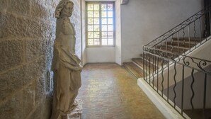 Un muro de piedra con una estatua, una ventana con vistas y una escalera con barandilla de metal.