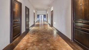 Un largo pasillo con puertas de madera oscura y un suelo con diseño.