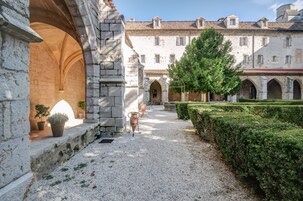 Un patio con arquitectura de piedra, un sendero de grava y un seto bien cuidado.