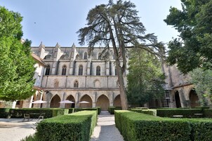 Un edificio histórico con patio, paseos con arcos y setos cuidados.