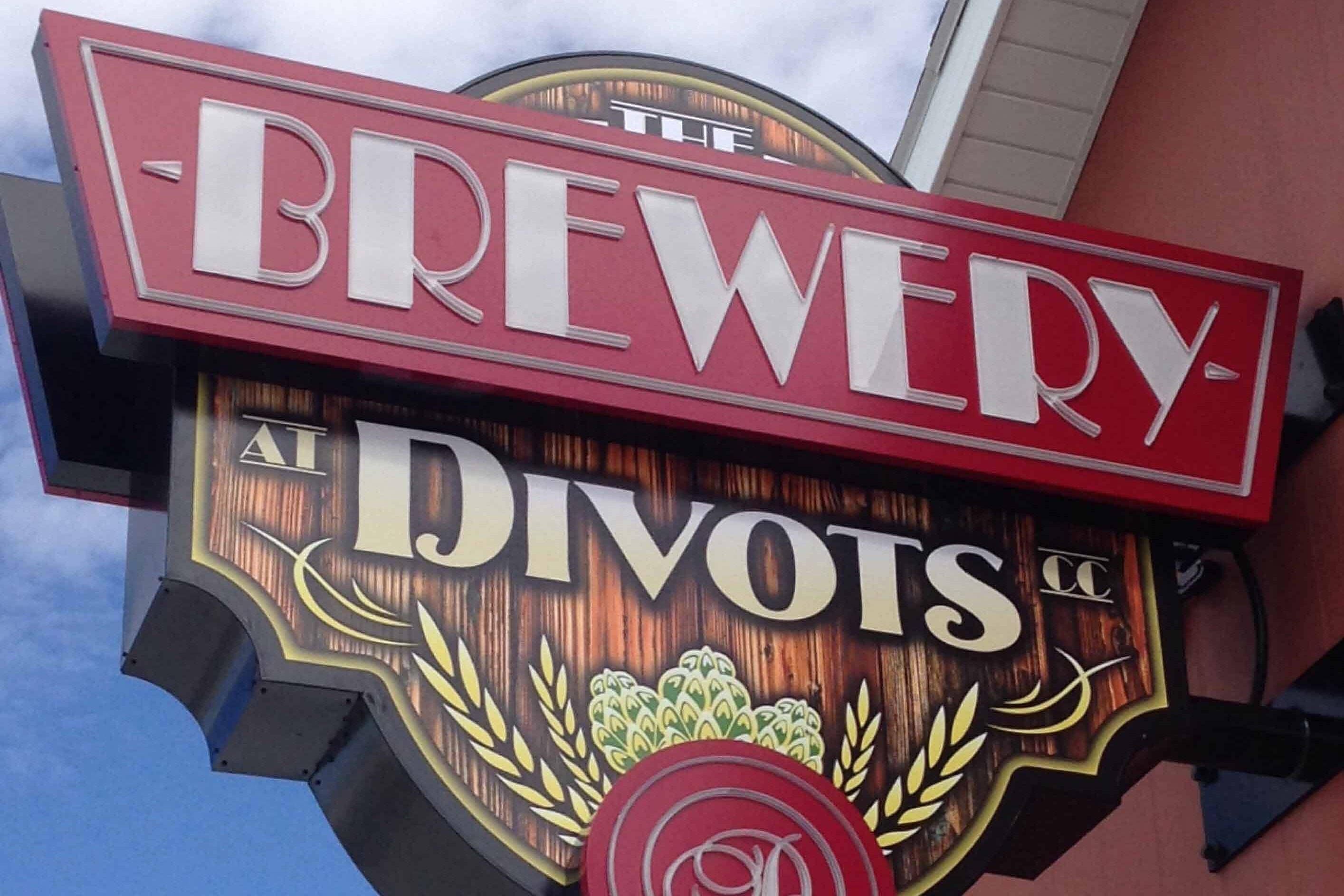 A sign for 'The Brewery Divots' with a wooden design and laurel wreaths.