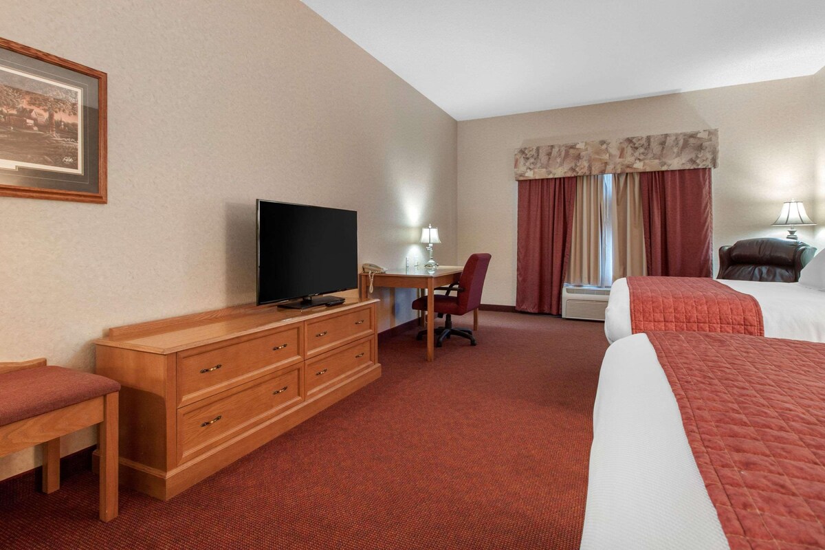 A hotel room with a bed, a desk with a chair, a television, and a dresser.